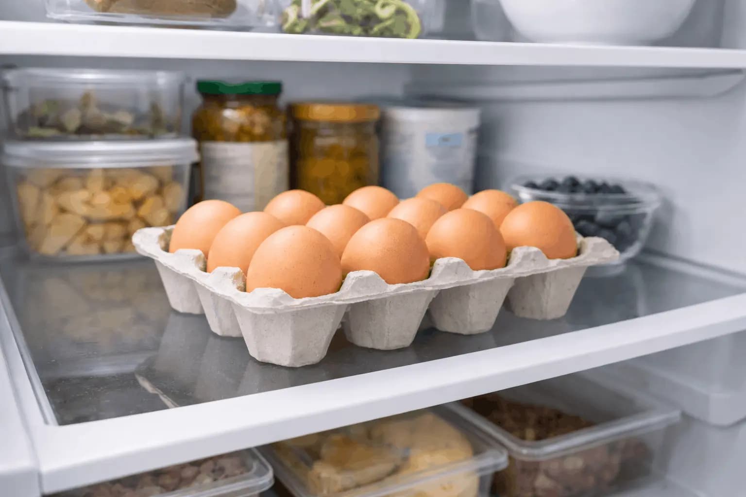 Egg carton stored properly on middle shelf of refrigerator demonstrating correct egg storage location